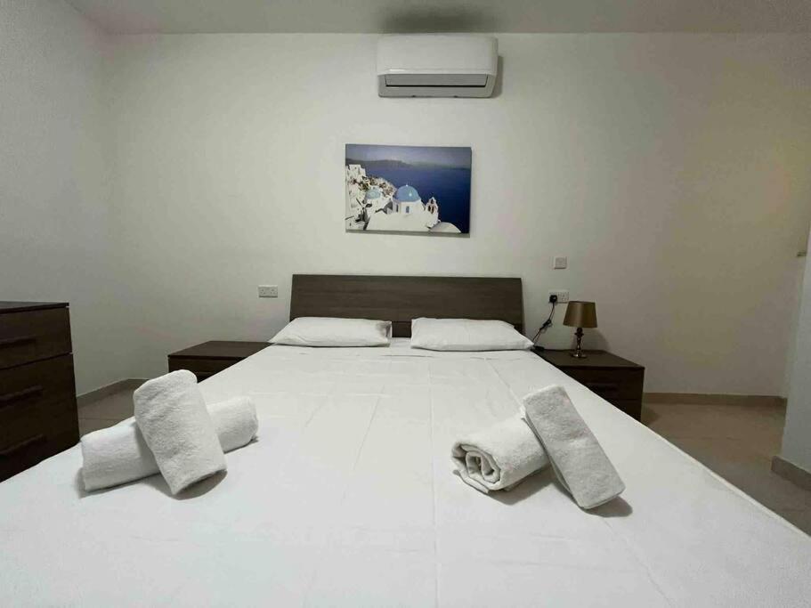 una camera da letto con un grande letto bianco con asciugamani di Lovely 3 Bedroom Condo a San Giuliano