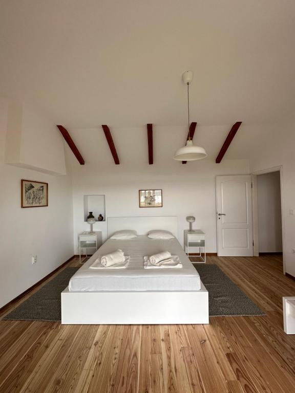 a white bedroom with a bed and a wooden floor at Matisse Residence in Nerezine