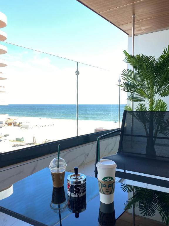 un tavolo con due tazze da caffè sopra con vista sulla spiaggia di Eva Del Mar - Sea view - Mamaia Nord a Mamaia