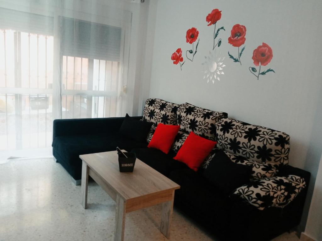 Casa Luz y Azahar في سان خوان ديل بويرتو: غرفة معيشة مع أريكة سوداء ووسائد حمراء