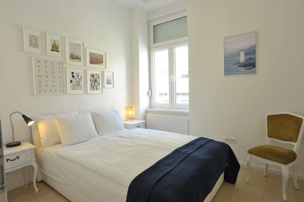 a white bedroom with a bed and a chair at Apartment Calliope in Zagreb