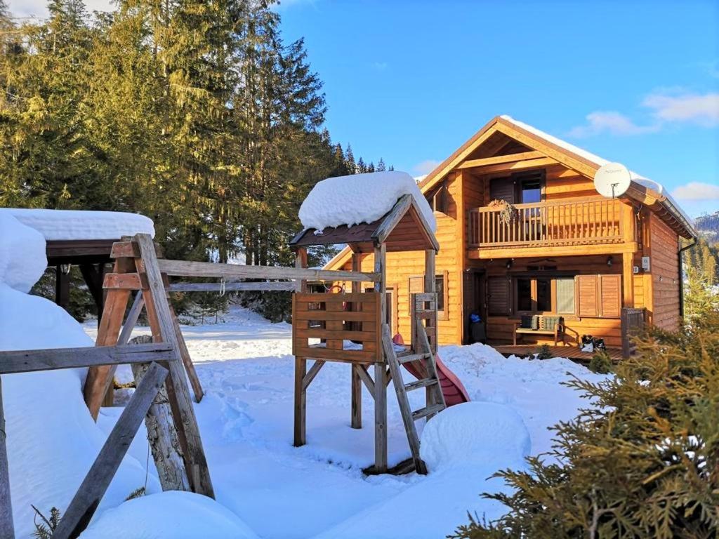 una cabaña de madera en la nieve con cenador en Chata Simon, en Nižná Boca