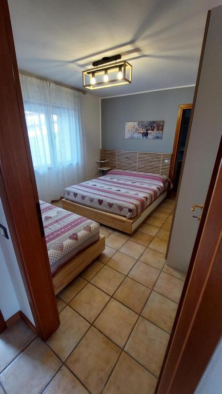 una camera con 2 letti e un pavimento piastrellato di Villa Augusta ad Auronzo di Cadore