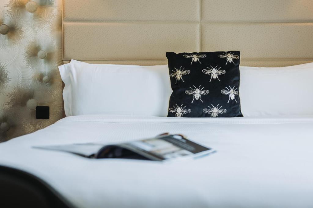 a bed with a black and white pillow and a magazine at Hôtel La Villa Cannes in Cannes