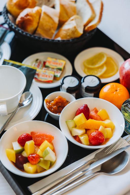 a tray of food with bowls of fruit and bread at Hôtel La Villa Cannes in Cannes