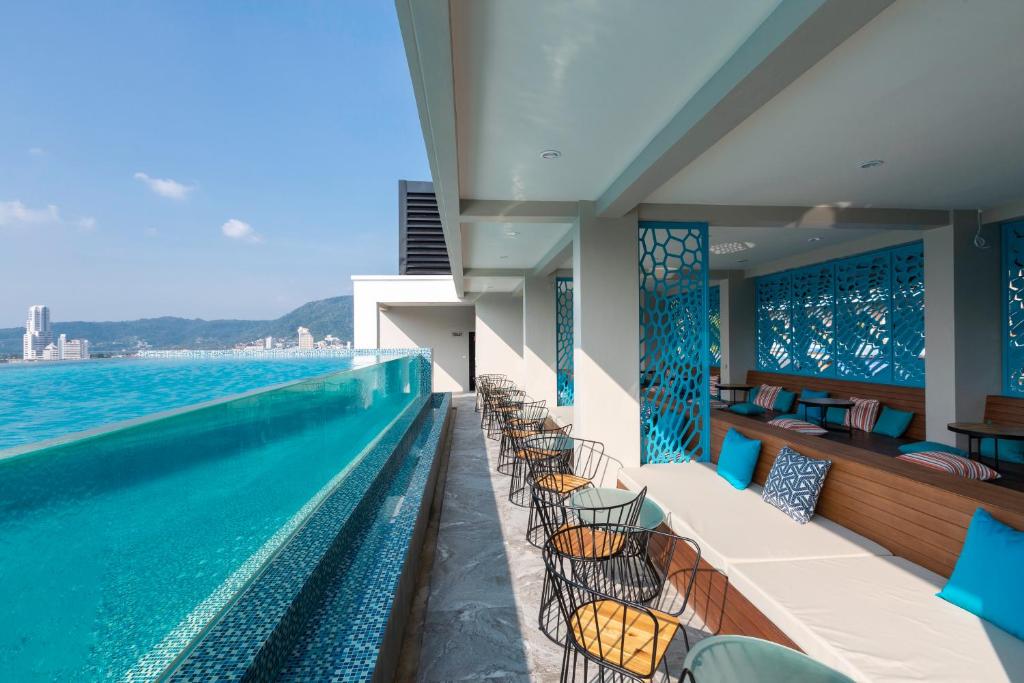 a swimming pool with chairs next to the water at Triple L Hotel Patong Beach Phuket in Patong Beach