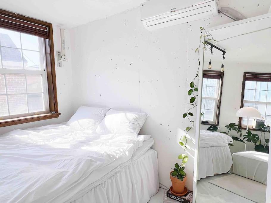a white bedroom with a bed and a mirror at Urban Garden French in Seoul