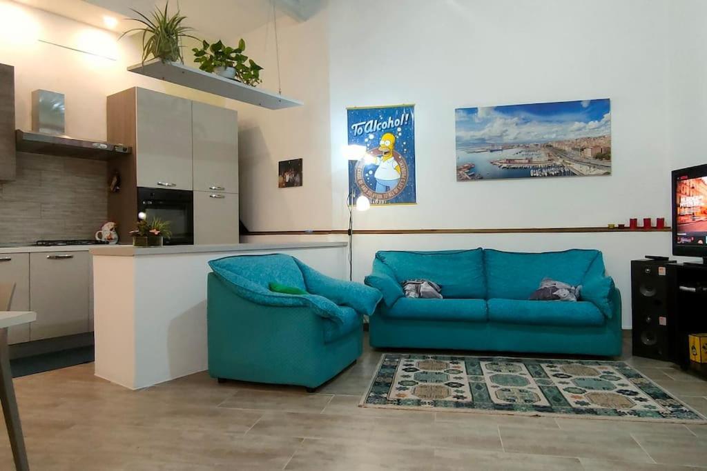 een woonkamer met een blauwe bank en een keuken bij Delizioso appartamento in Dolianova