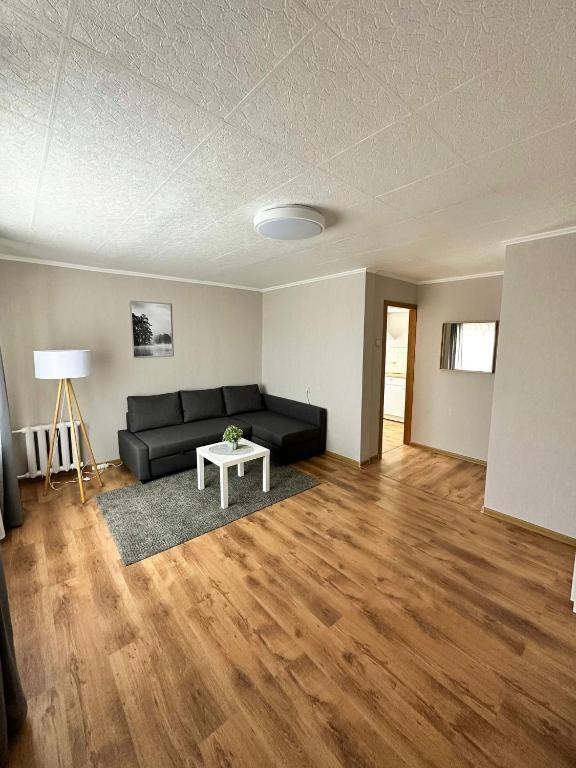 Sea side apartments في يورمالا: غرفة معيشة مع أريكة سوداء وطاولة