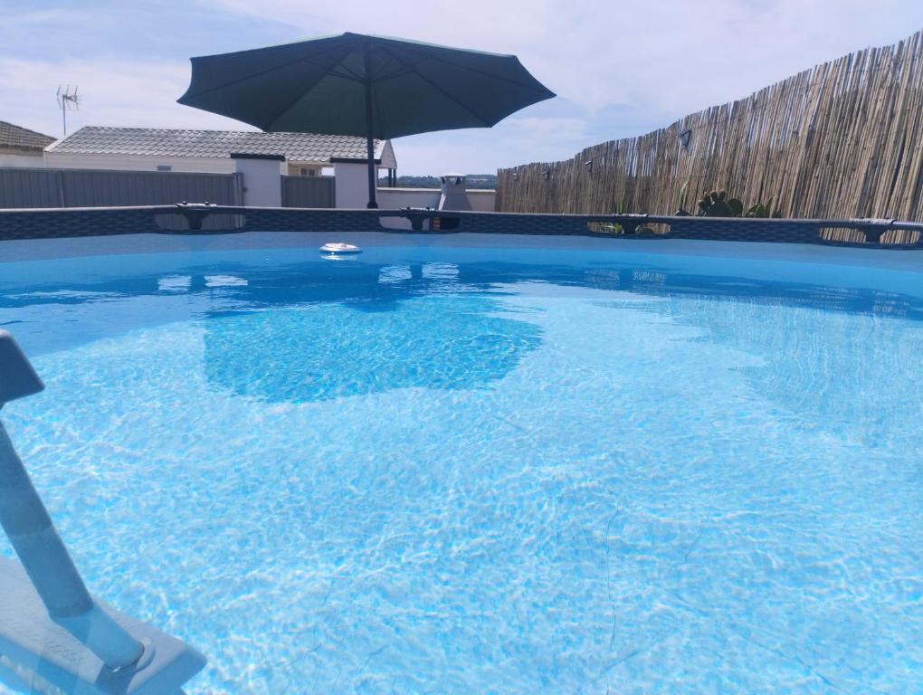 een groot blauw zwembad met een parasol bij LA BRISA in Cádiz