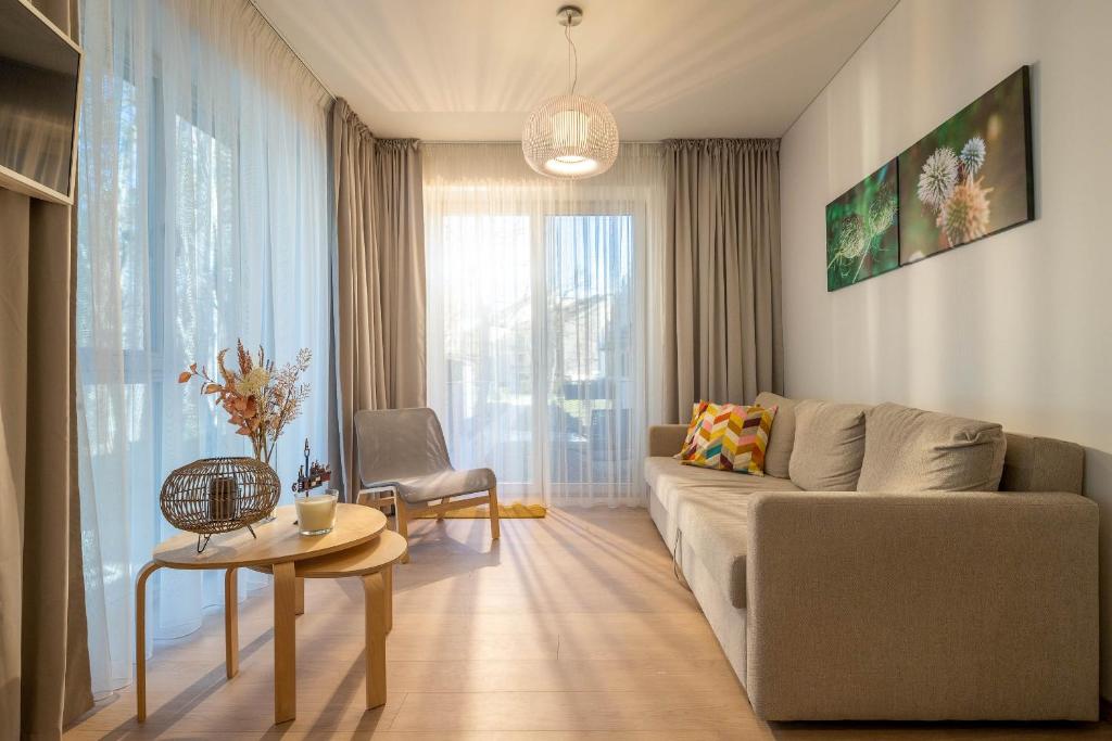 ein Wohnzimmer mit einem Sofa und einem Tisch in der Unterkunft Sunset Apartment in Juodkrantė