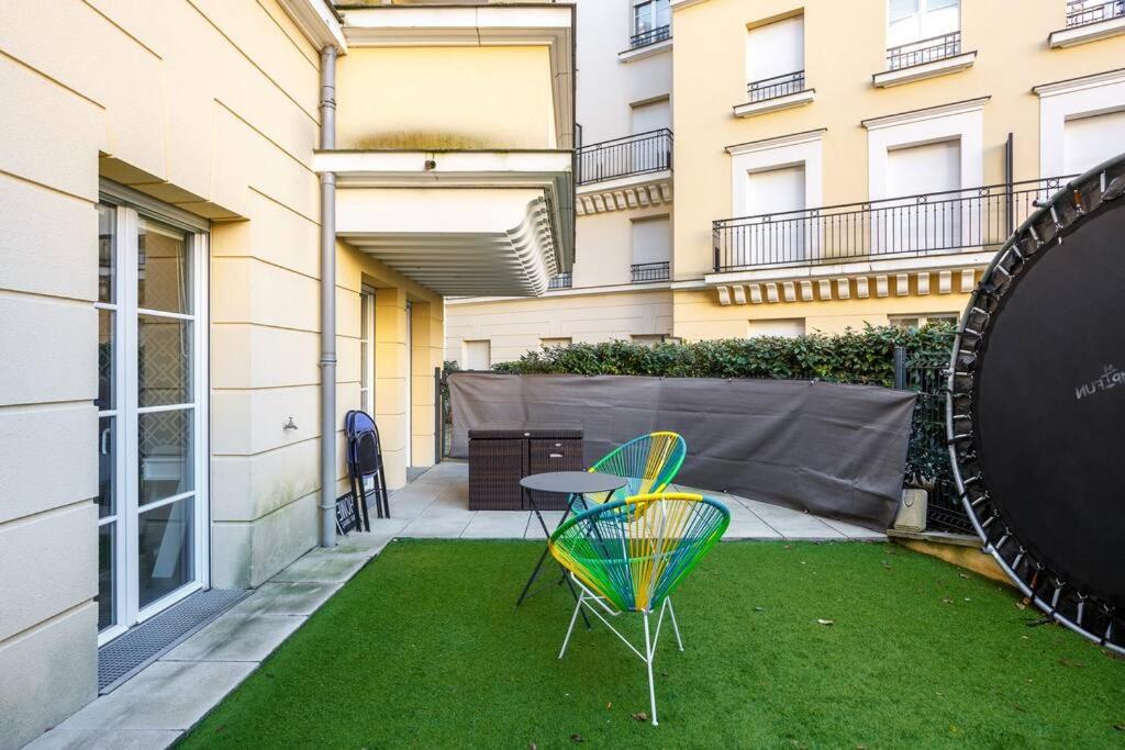 a patio with a table and chairs on the grass at Apt 6P - Standing RER Tram Paris Orly Velizy in Le Plessis-Robinson