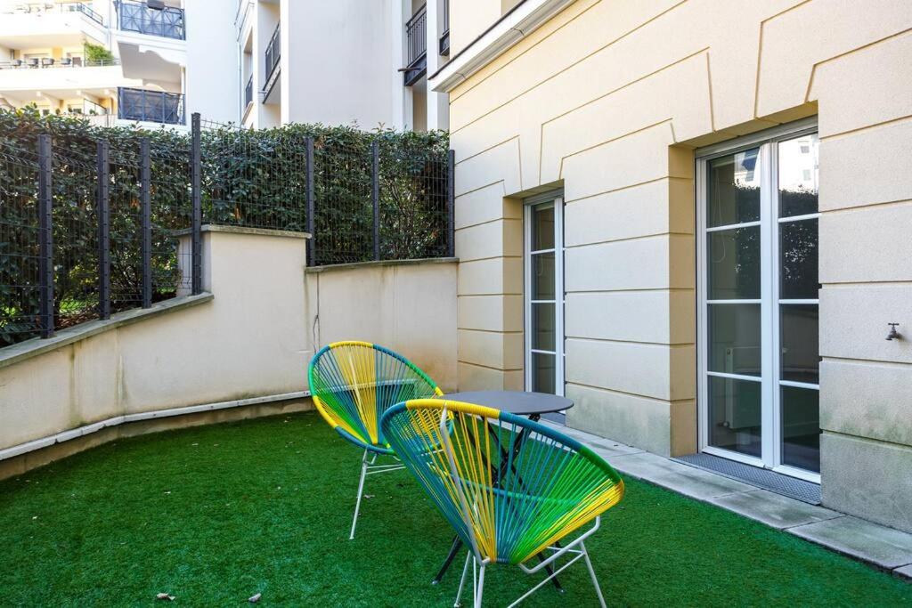 two chairs and a table on a patio with grass at Apt 6P - Standing RER Tram Paris Orly Velizy in Le Plessis-Robinson
