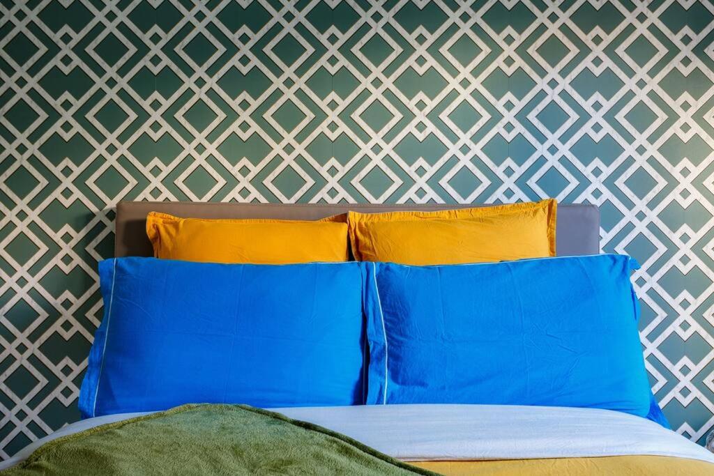 a bedroom with blue and yellow pillows and a wall at Apt 6P - Standing RER Tram Paris Orly Velizy in Le Plessis-Robinson