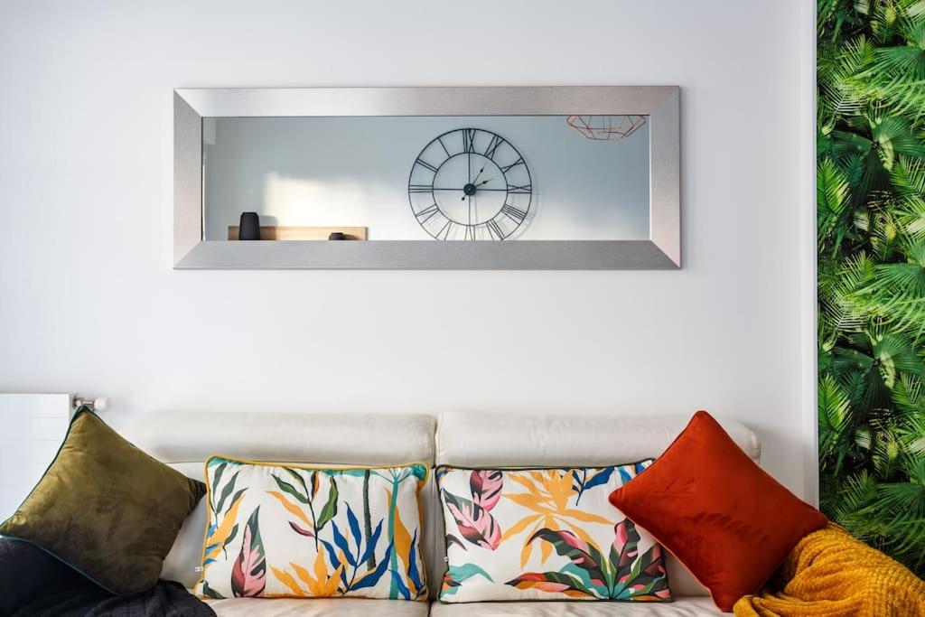 a mirror on the wall above a couch with pillows at Apt 6P - Standing RER Tram Paris Orly Velizy in Le Plessis-Robinson