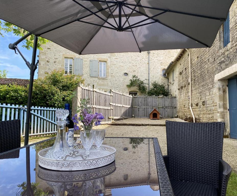 a table with an umbrella on a patio at Gîte du Rossignol entre lac et forêt in Mervent