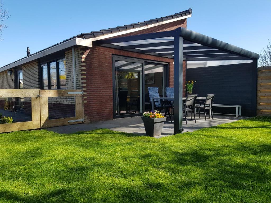 een paviljoen met een tafel en stoelen op een gazon bij Luxe vakantiebungalow met omheinde tuin voor hond en kinderen in Dirkshorn