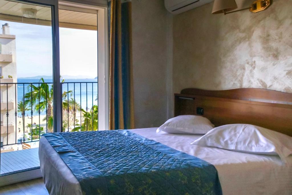 - une chambre avec un lit et une vue sur l'océan dans l'établissement Anglade Hotel, au Lavandou