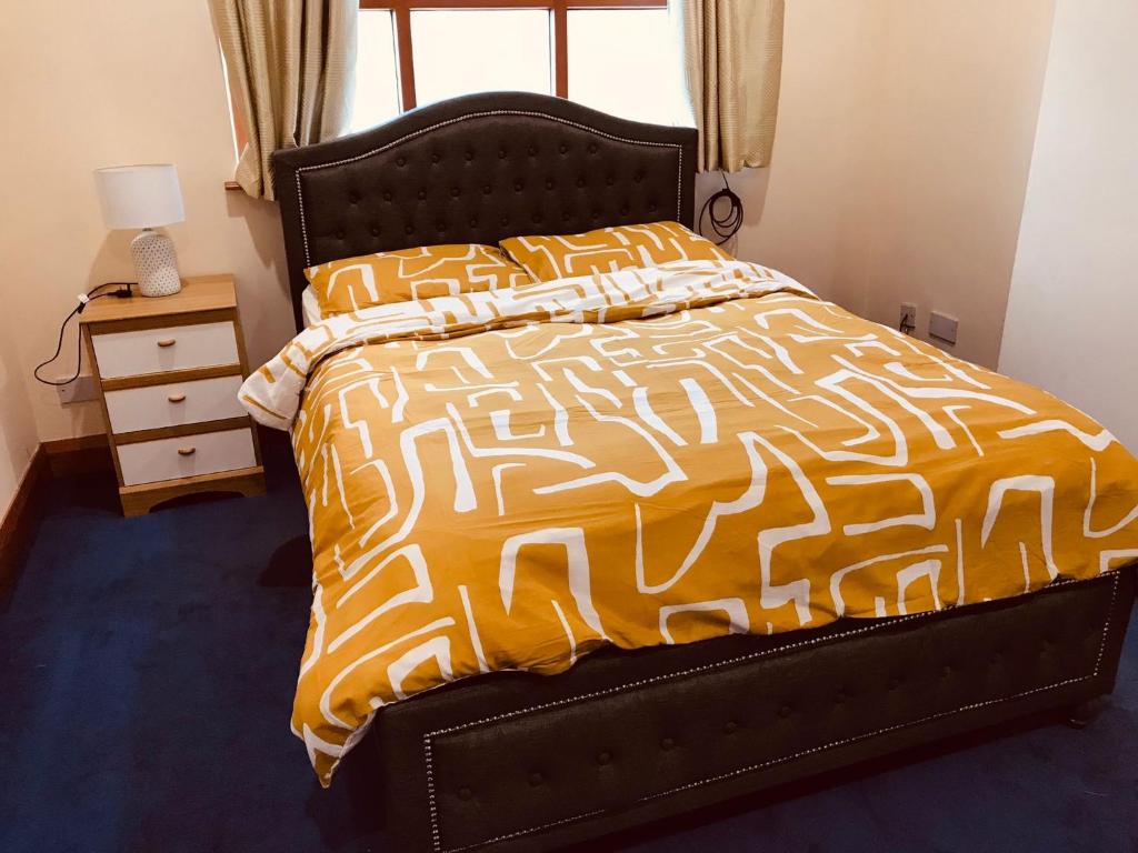 a bedroom with a bed with an orange and white comforter at Lovely 3 bedroom apartment in Buncrana in Buncrana