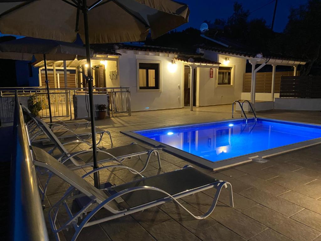 a swimming pool with chairs and an umbrella at night at Villa Valmas Private Escape in Skiathos