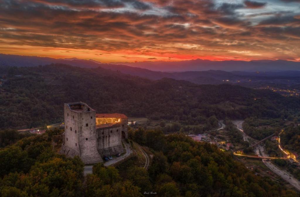 a castle on a hill with a sunset in the background at TENUTA CASTEL DELL'AQUILA in Gragnola