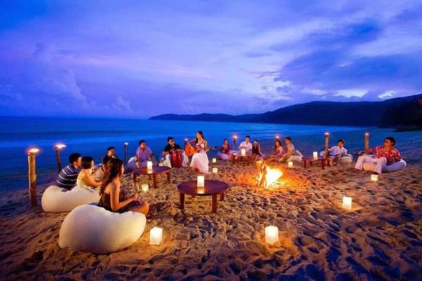 un grupo de personas sentadas en la playa con velas encendidas en Colva Beach Samaira GuestHouse & Apartments, en Colva