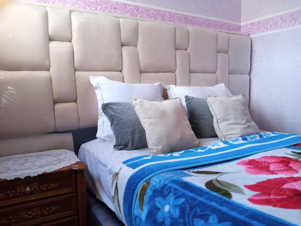 um quarto com uma cama com uma cabeceira branca e almofadas em salwa em Ifrane