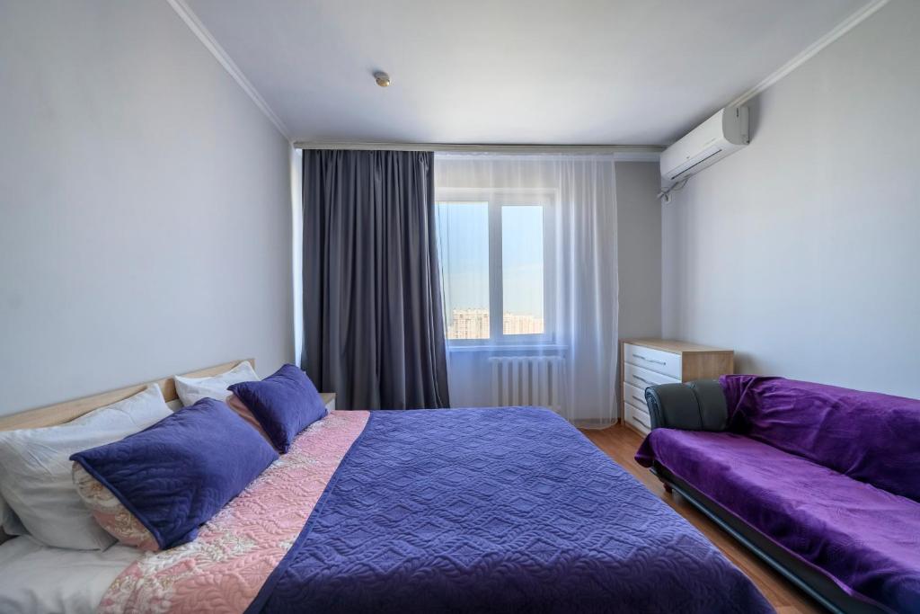 een slaapkamer met een paars bed en een bank bij ЖК Айгерим in Alma-Ata