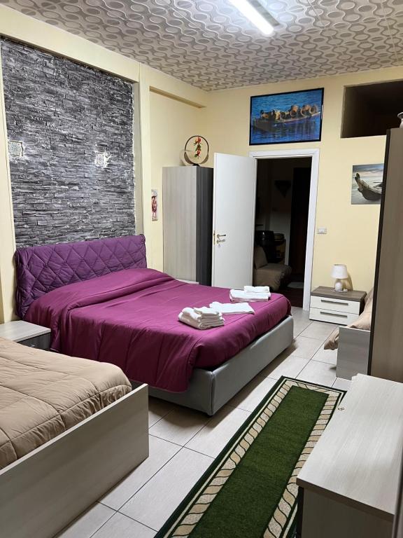 - une chambre avec un lit violet et un mur en briques dans l'établissement Luxury Apartment Golden Dreams, à Reggio de Calabre
