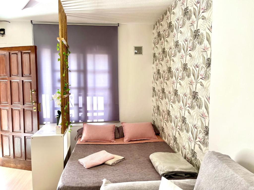 Habitación con sofá y 2 almohadas rosas. en Acogedor loft en recinto privado - Terapia Salada, en Estepona