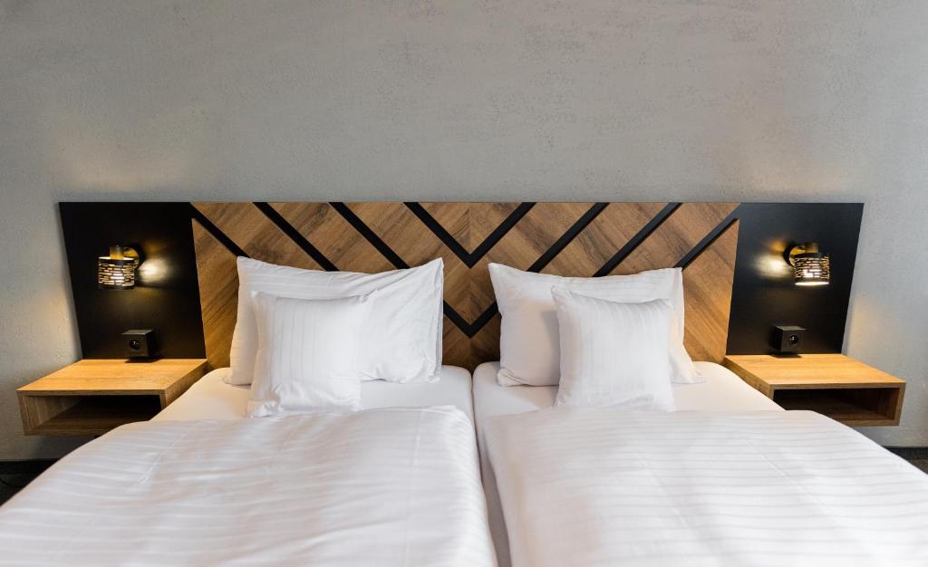 two beds in a hotel room with white sheets and pillows at Hotel Carrera in Rimavská Sobota
