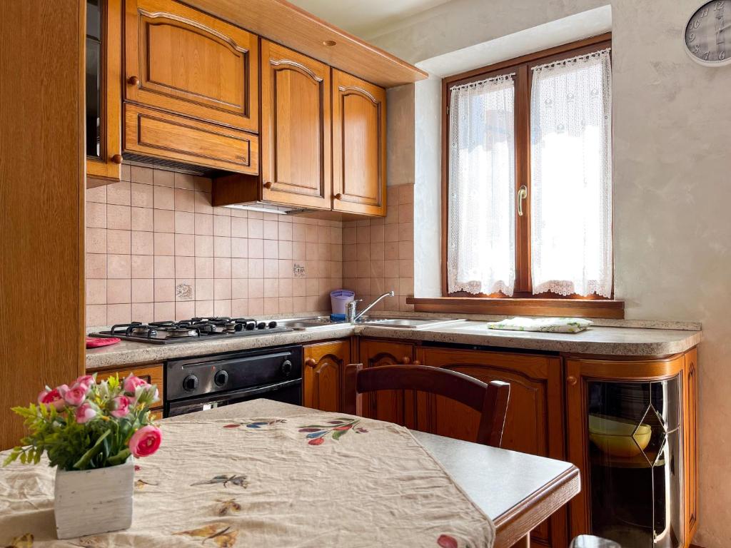 a kitchen with wooden cabinets and a table with a vase of flowers at Al centro e vicina al lago in Farra dʼAlpago