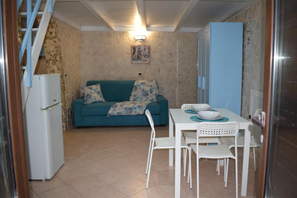 - un salon avec une table, des chaises et un canapé bleu dans l'établissement Chicca marina, à Torre Canne