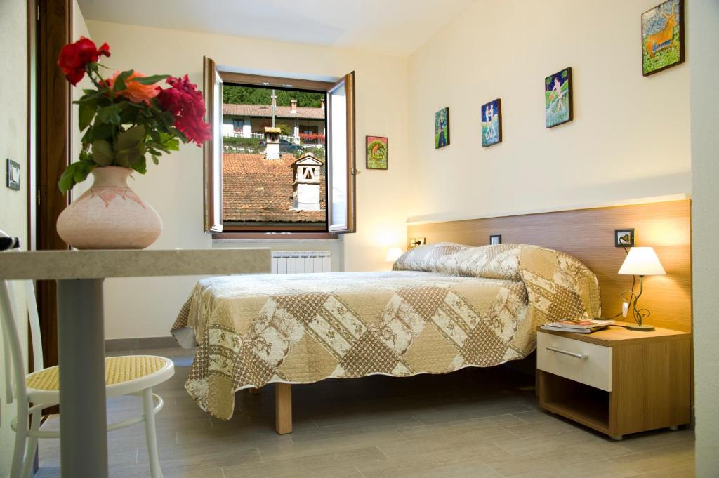 ein Schlafzimmer mit einem Bett und einer Vase aus Blumen auf einem Tisch in der Unterkunft Residence Le stanze dei Visconti in Voltaggio
