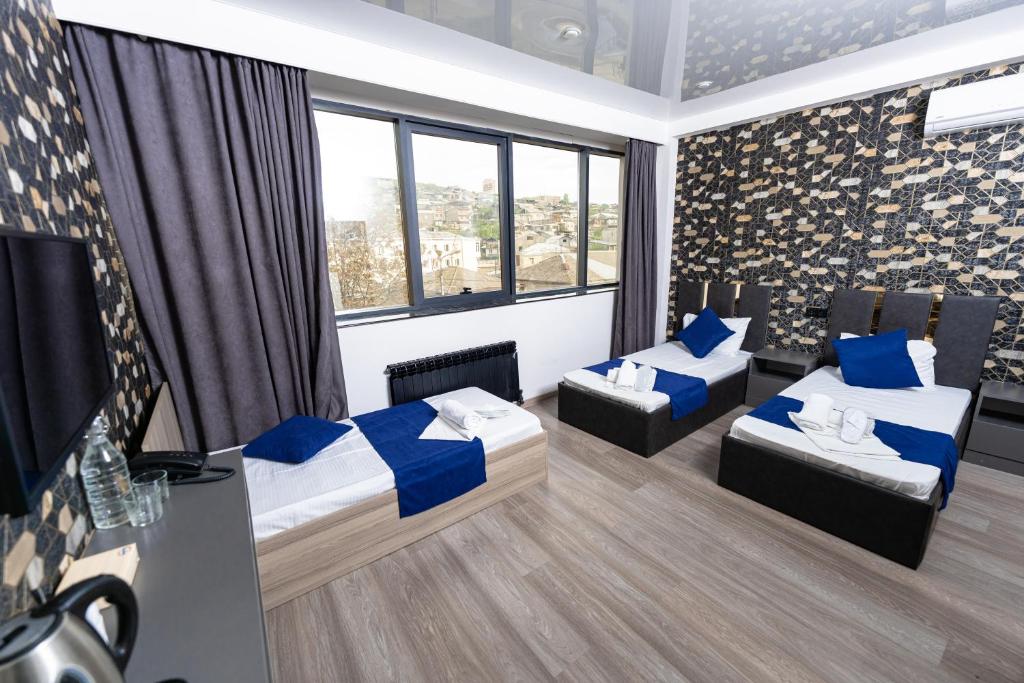 エレバンにあるBloom Hotel Yerevanのベッド2台とテレビが備わる客室です。
