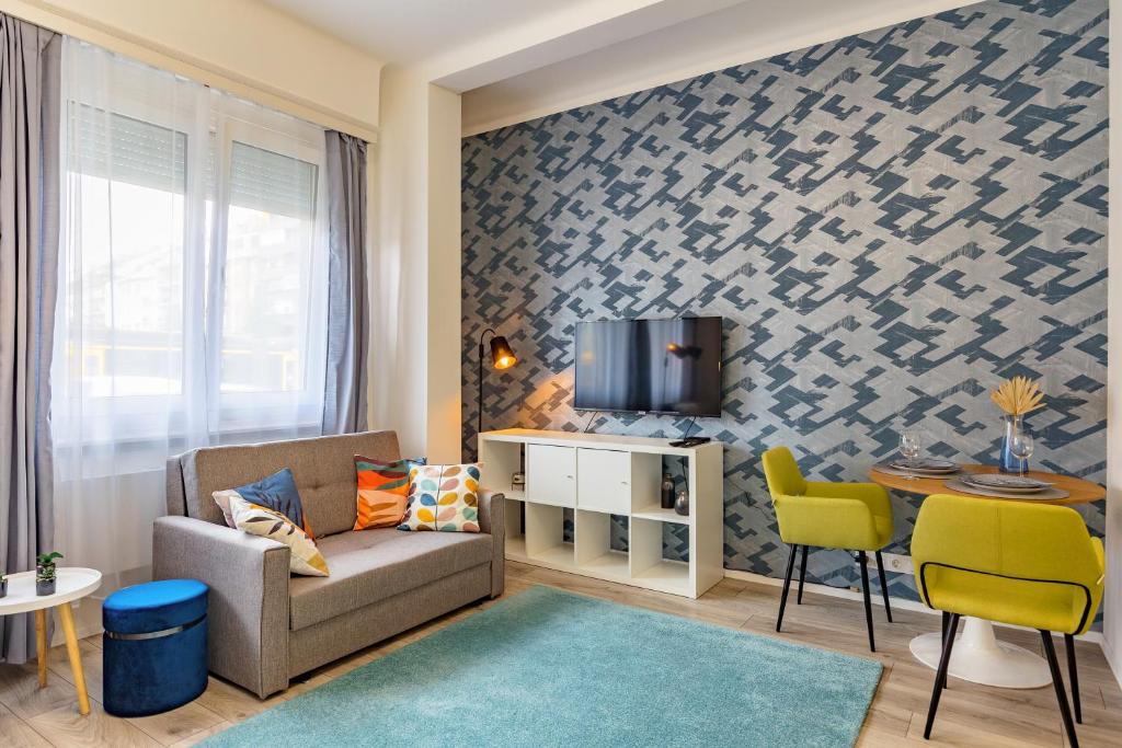 a living room with a couch and a tv on a wall at ALLEE BUDA Apartment in Budapest