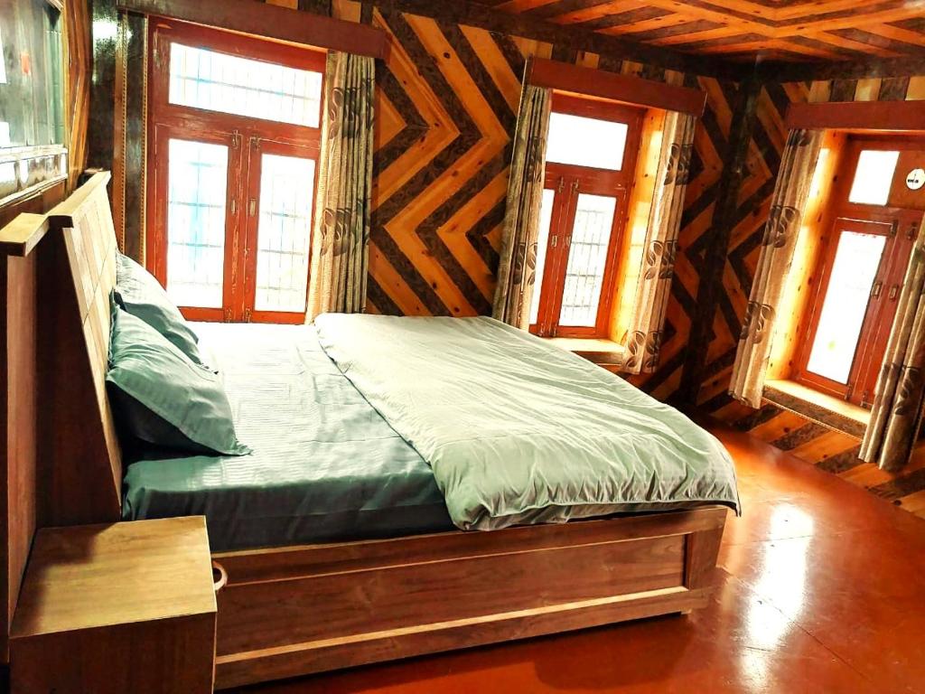 a bed in a wooden room with two windows at Yangling House in Sissu