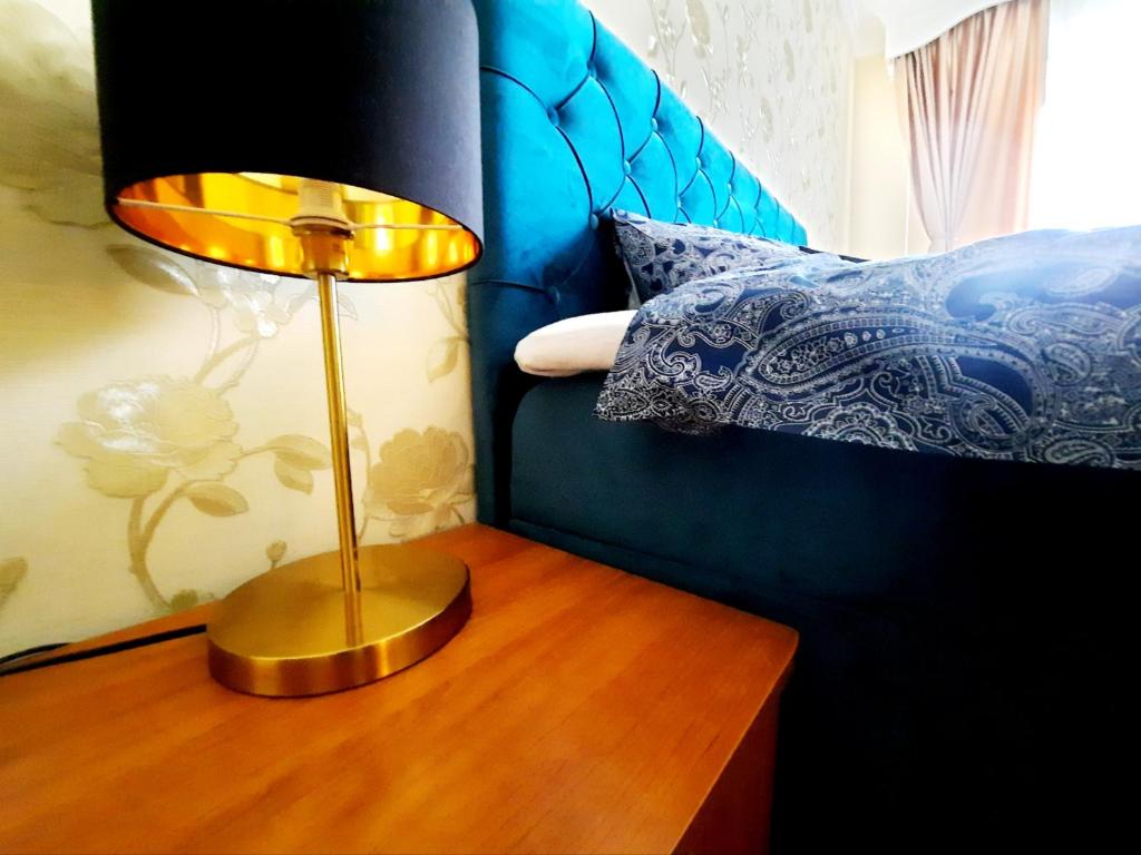 une lampe sur une table en bois à côté d'un lit dans l'établissement Apartment on Dzenu Street, à Riga