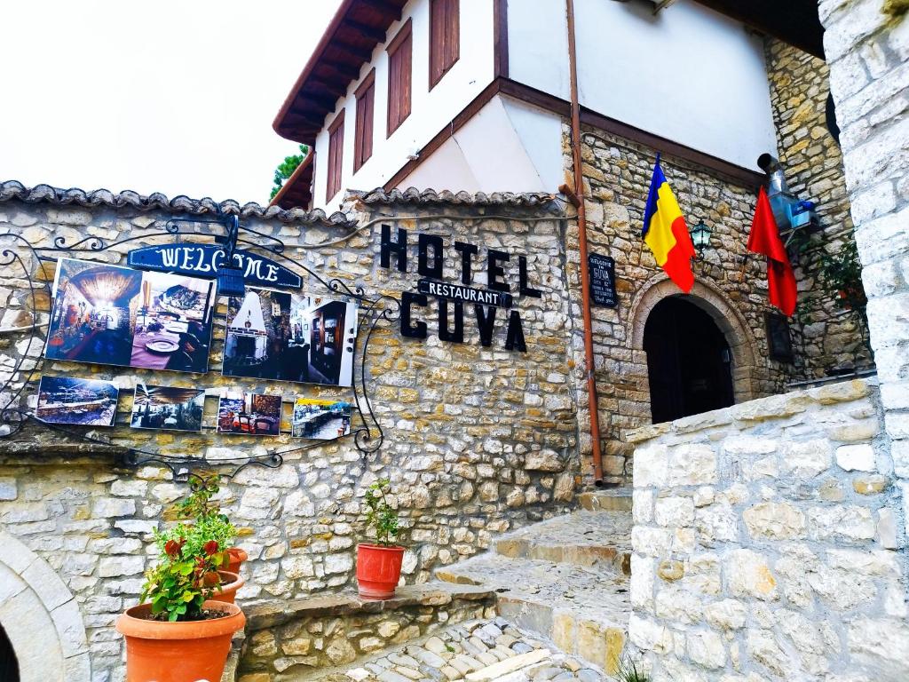 um edifício de pedra com bandeiras na lateral em Guva Mangalem Hotel Restaurant em Berat