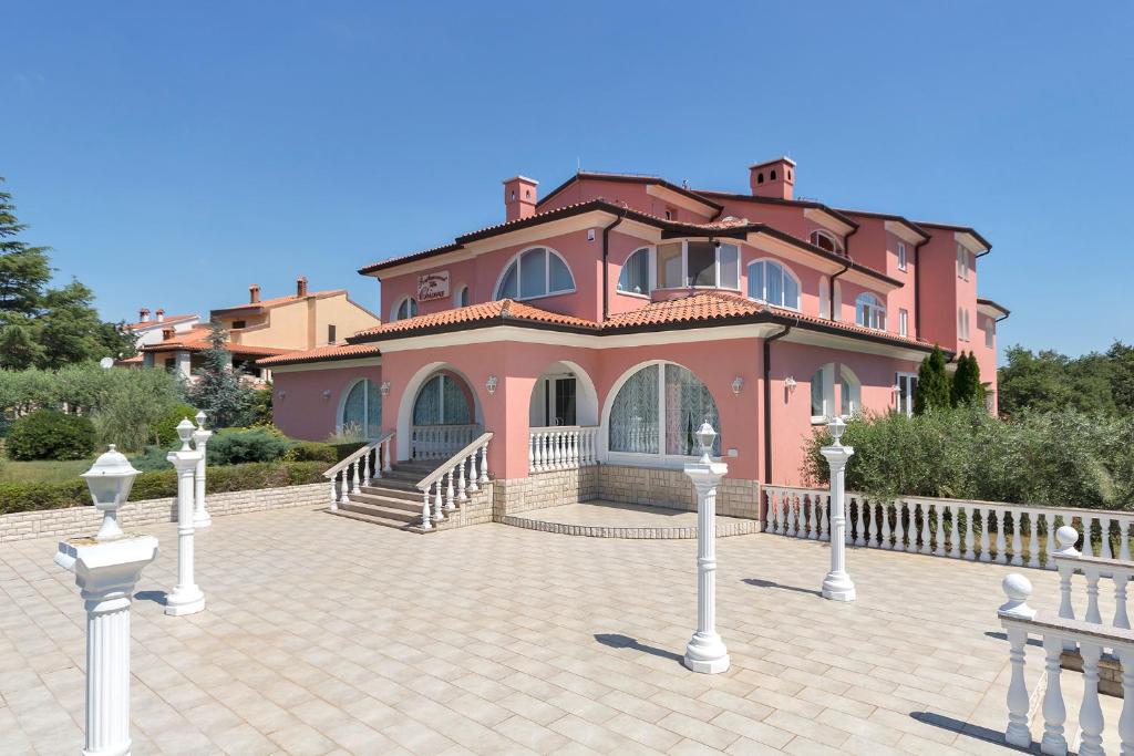 ein großes rosafarbenes Haus mit weißen Pfosten davor in der Unterkunft Villa Chiara in Krnica