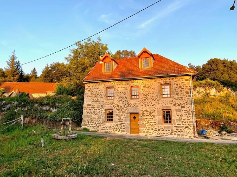 una casa in pietra con tetto arancione in un campo di La Maison du Bonheur & Spa 