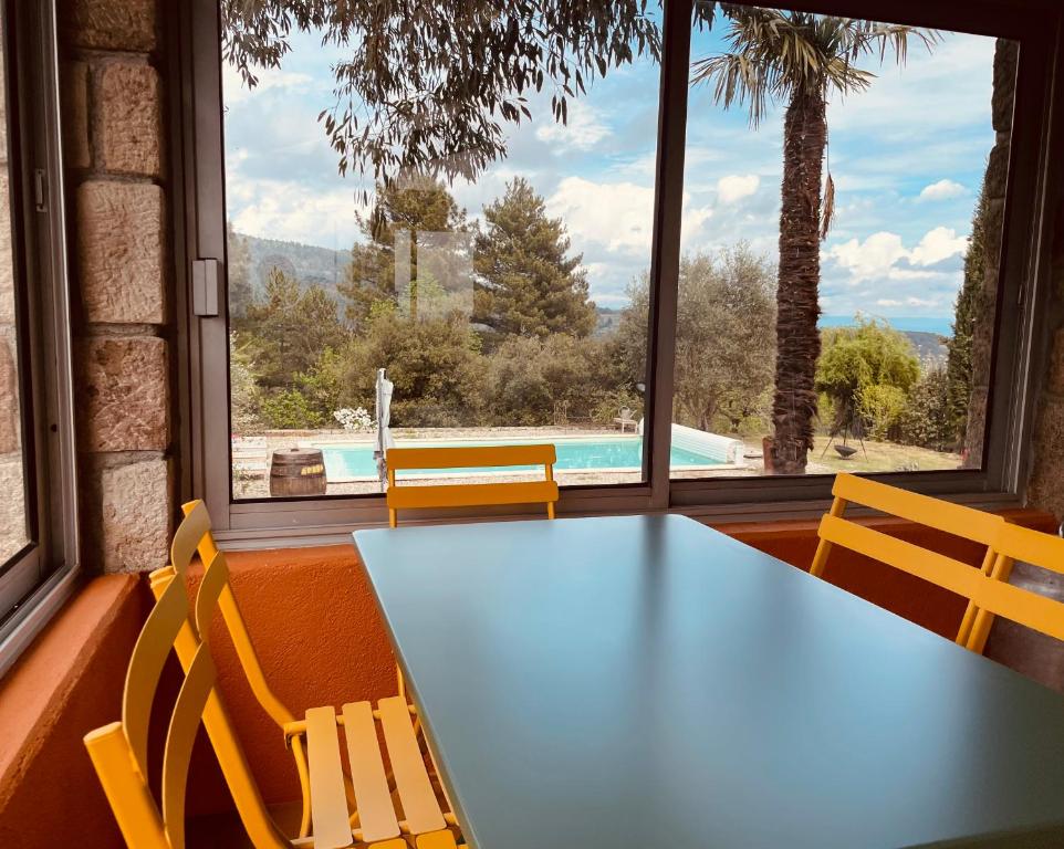 a table and chairs in a room with a view of a pool at Le Planzollais in Planzolles