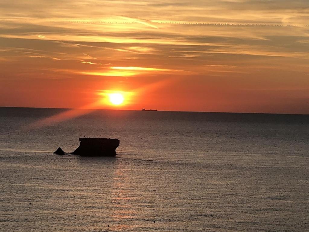- un coucher de soleil sur l'océan avec un bateau dans l'eau dans l'établissement Le petit cottage le portel, à Le Portel
