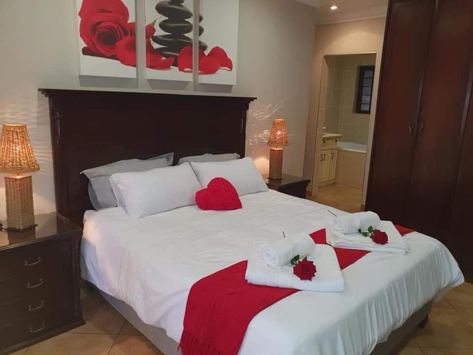 een slaapkamer met een groot bed en rode en witte handdoeken bij Roosthaven Guesthouse in Centurion