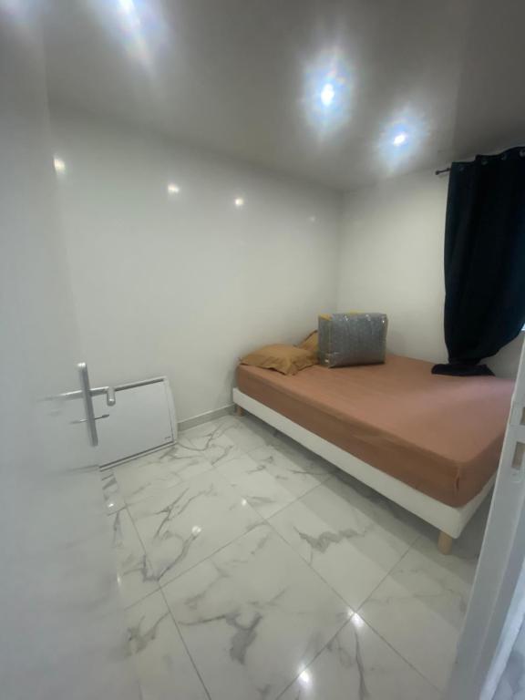 een kleine kamer met een bed en een kruis aan de muur bij Appartement mignon drancy in Drancy