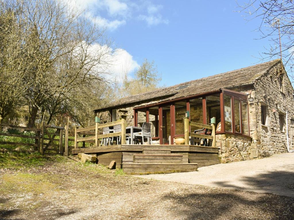 a stone house with a porch and a fence at Red Squirrel Haven in Hawes