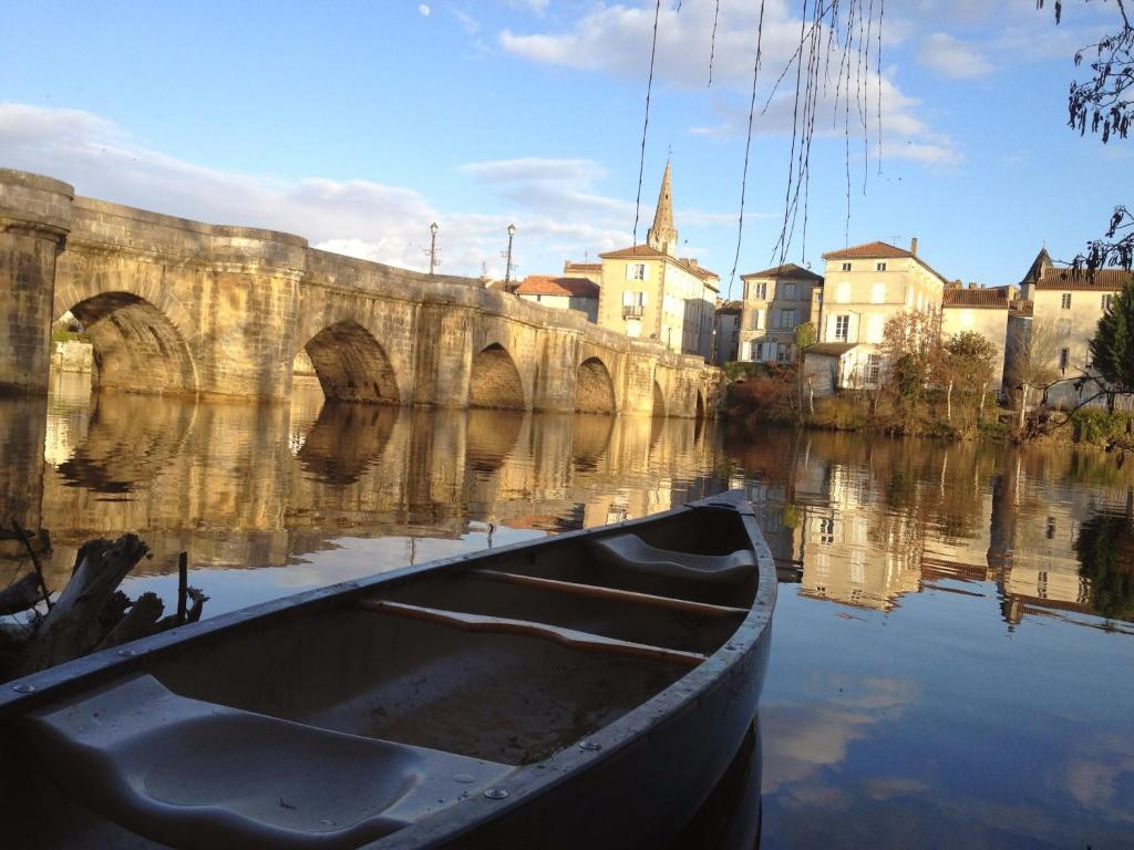 a boat sitting in the water next to a bridge at Pont Vieux in Confolens