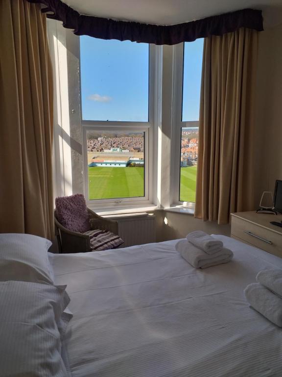 a bedroom with a bed and a large window at Dickie's View in Scarborough