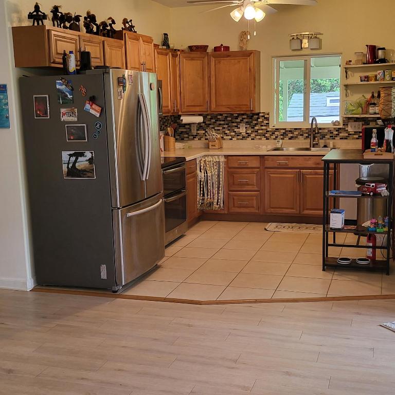 a kitchen with a stainless steel refrigerator and wooden cabinets at Hoomaikai Blessings in Keaau