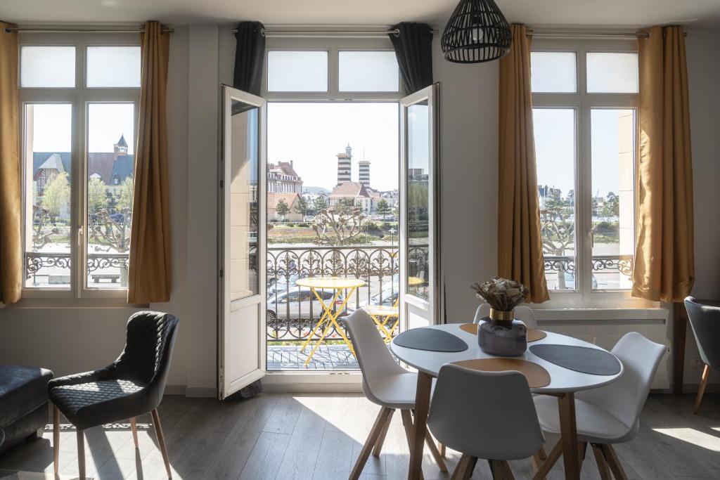 a living room with a table and chairs and a balcony at Le BAC FLEURI in Trouville-sur-Mer